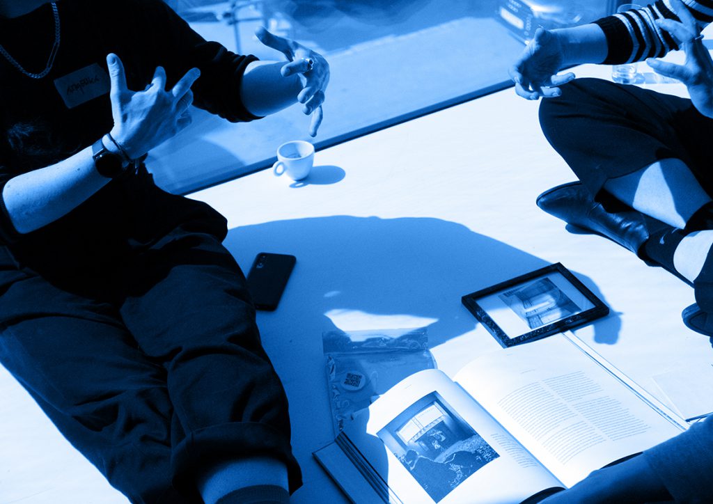 Photo in blue tone with hands, a coffee cup and a book