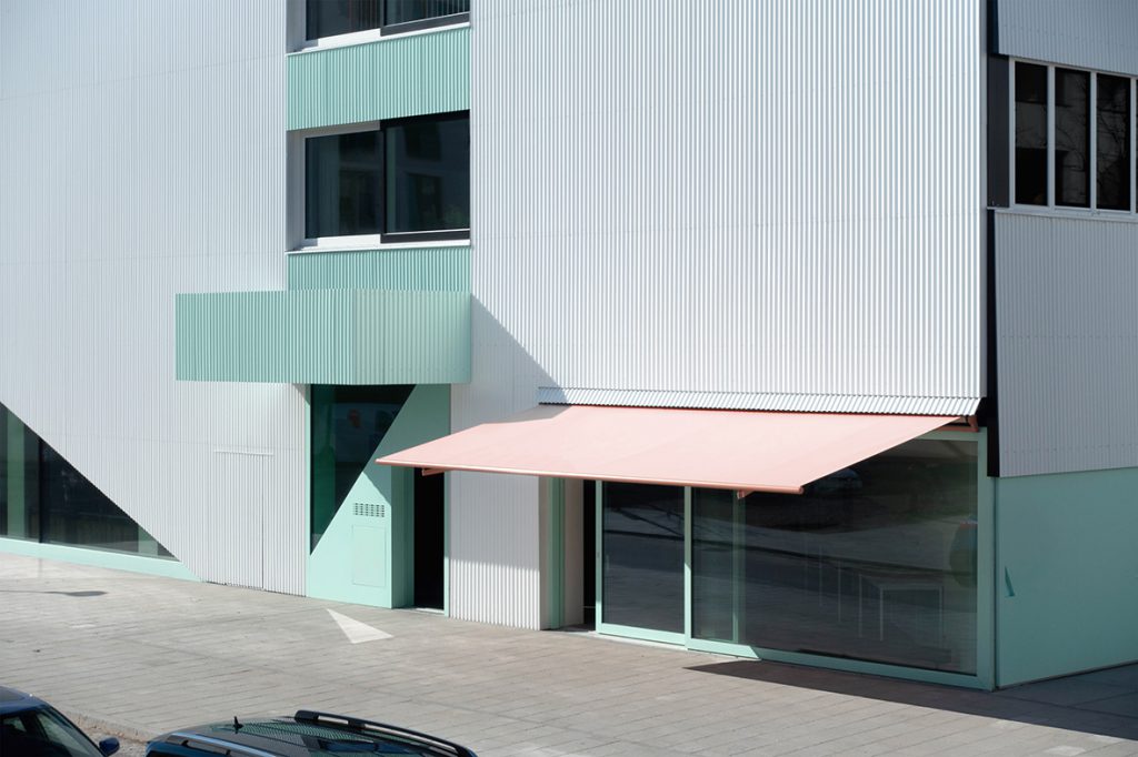 Gebäudefassade mit gerillter Oberflächer und hellgrünen-türkisen Elementen
