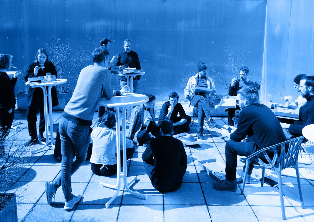 blue coloured photo with people sitting, standing and eating