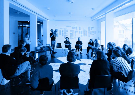 blaugefärbtes Foto mit mehreren Personen, die im Kreis sitzen