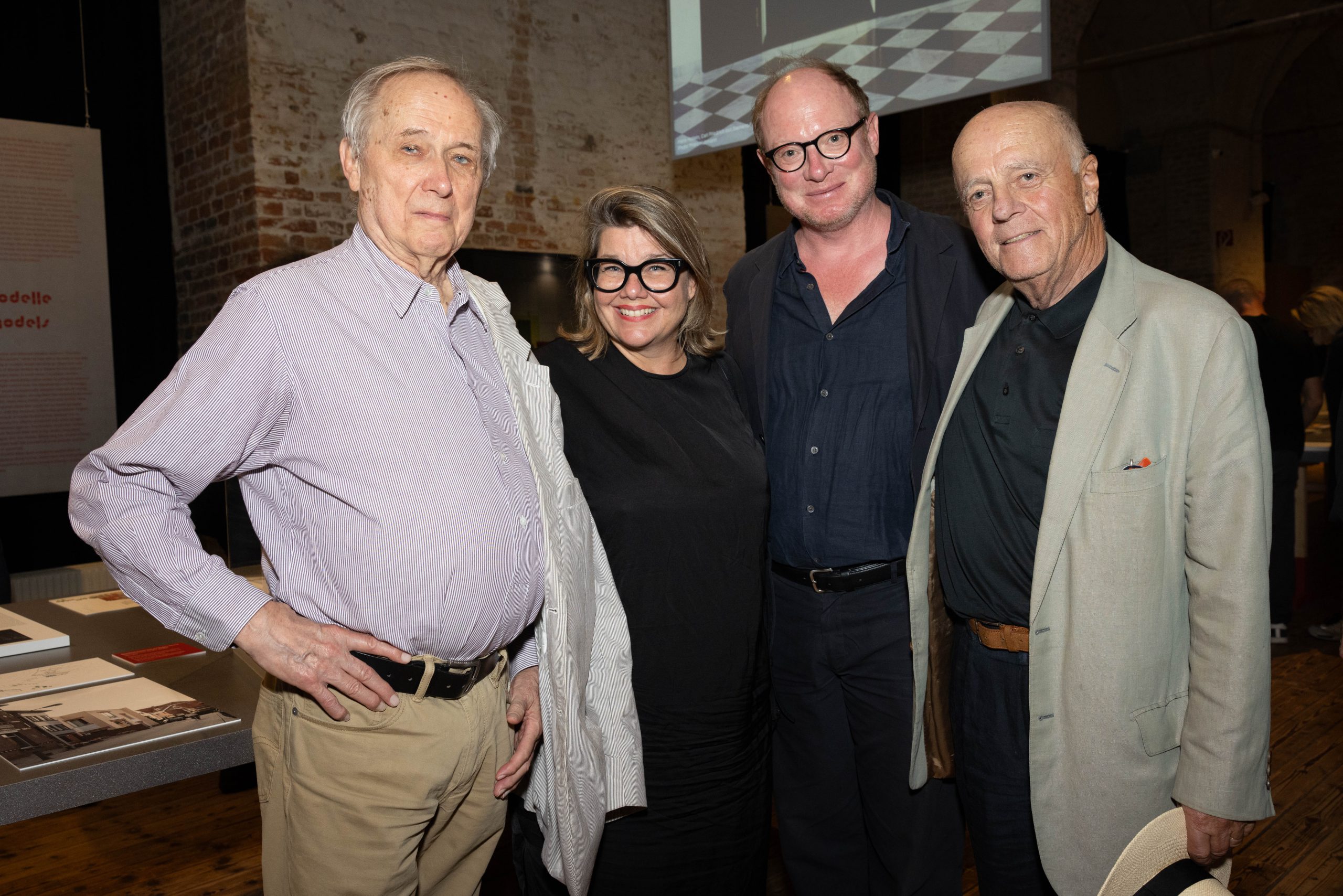 3 men and a woman with thick black glasses look into the camera