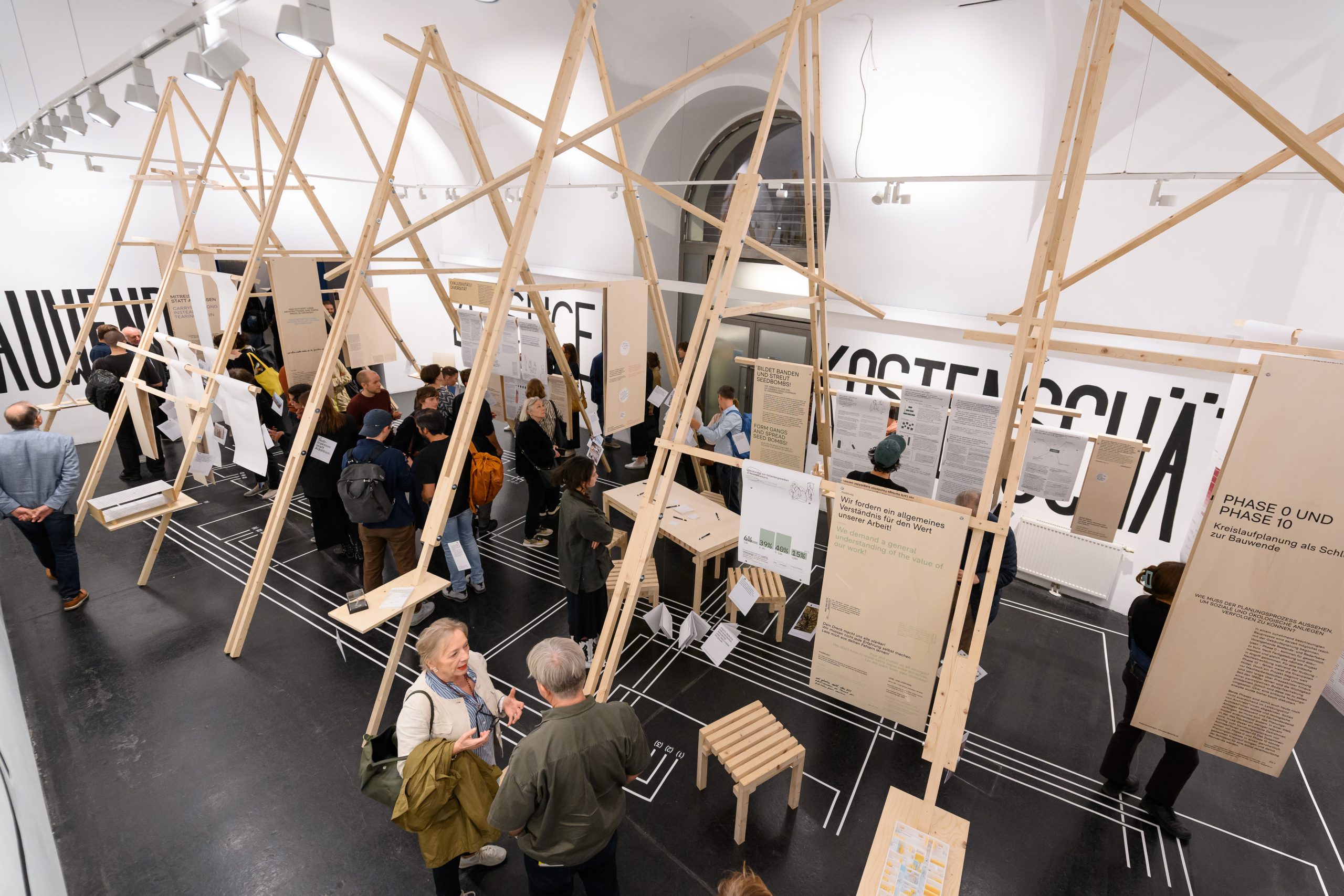 Exhibition space with many people and wooden scaffolding