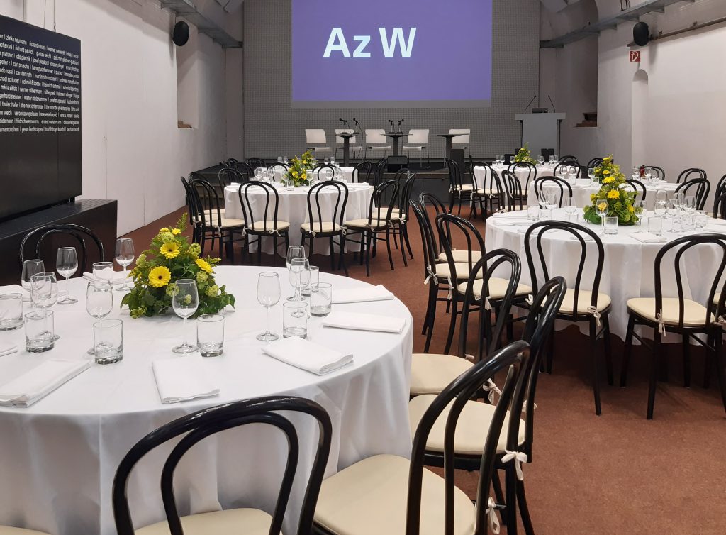 a few tables with black armchairs in a room with a projection with a blue background