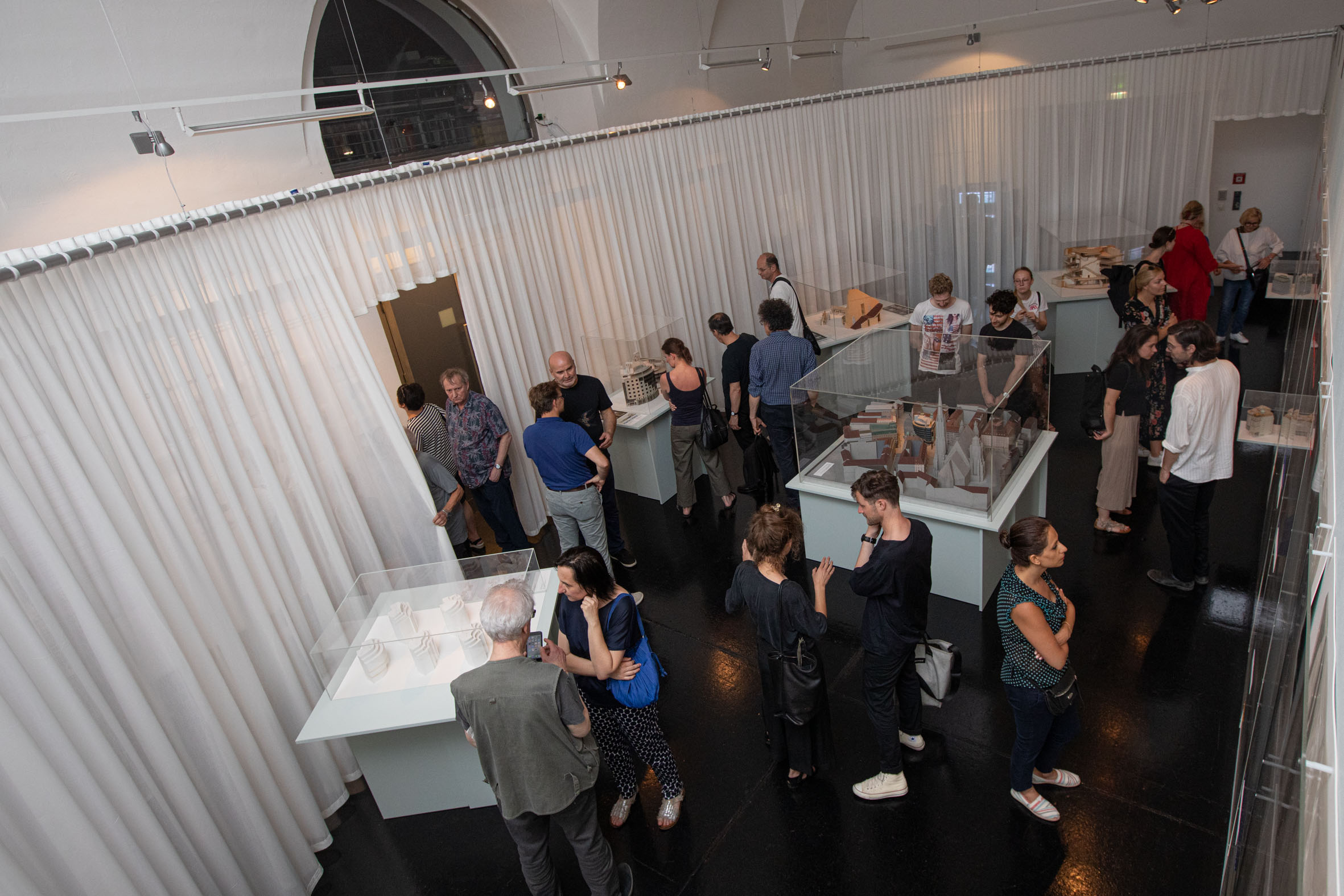 many people in a room with a curtain and some architectural models