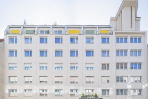 mehrstöckiges Haus mit heller Fassade und rechts oben eine Erhöhunh mit einem großen Kreuz