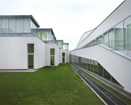 White building with inner courtyard and green meadow