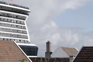 ein riesiges Kreuzfahrtschiff steht vor Häusern