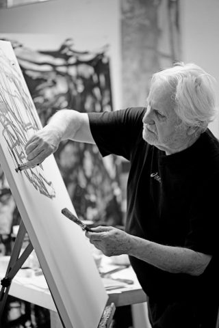 schwarz-weiß Foto mit älterem Mann der ein Bild malt