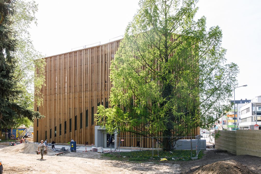 Building with wooden façade and large tree in front