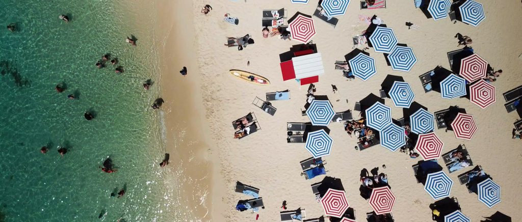 a beach with lots of blue and red striped parasols