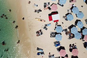 a beach with lots of blue and red striped parasols