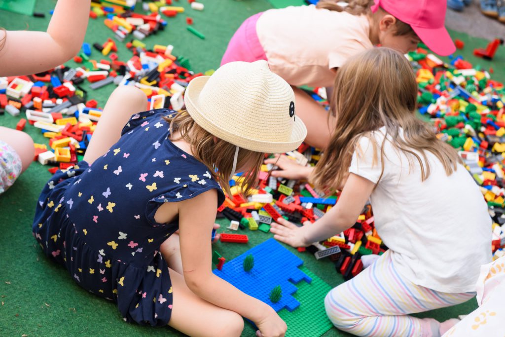 Kinder spielen mit Lego auf einer grünen Unterlage