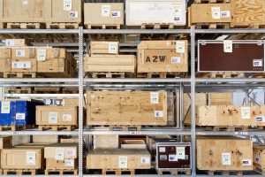 viele Holzkisten in einem Metallregal, auf einer steht AZW