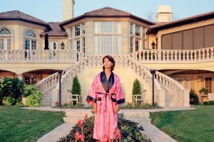 Woman in pink dressing gown in front of a house with large stairs on the left and right