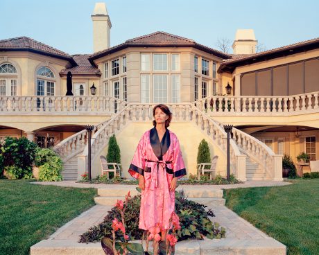 Woman in pink dressing gown in front of a house with large stairs on the left and right