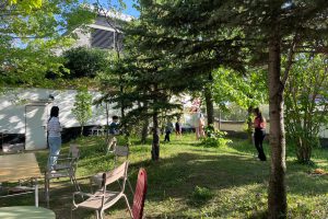 Meadow with trees, a few children and chairs at the edge