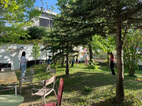 Meadow with trees, a few children and chairs at the edge