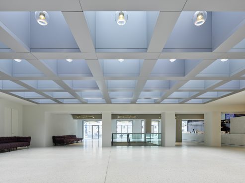 Large entrance hall in light white/grey tones, sofas on the left wall