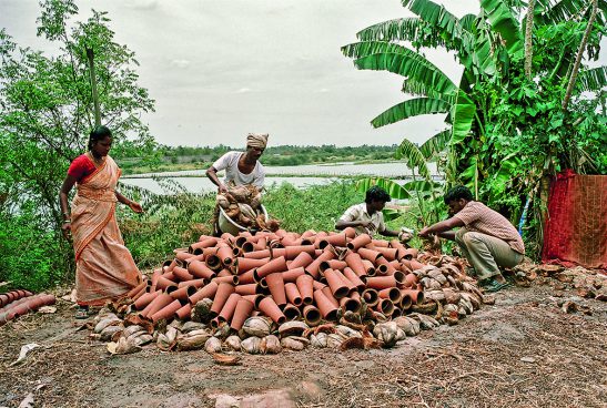 One woman and three men are working with terracotta cones, with a river visible behind them.