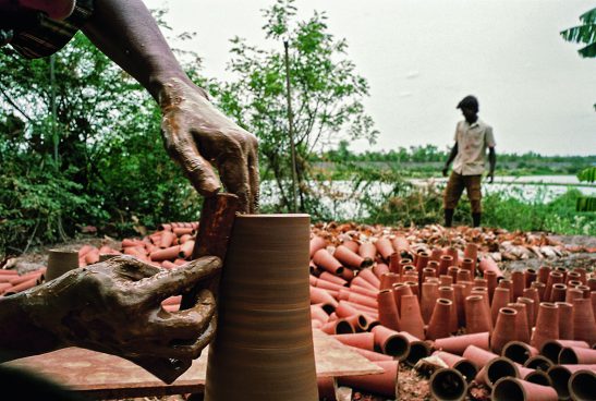 viele Terrakotta-Kegel, im Vordergrund wird einer gerade mit Händen gefertigt