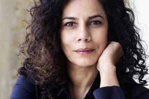 Frau mit dunklen lockigen Haaren und einem dunkelblauem Oberteil