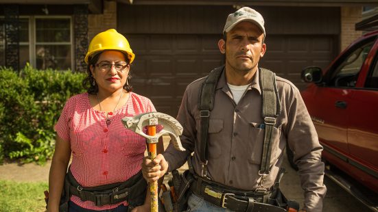 a woman with a yellow helmet and a man with a cap holding a tool in his hand