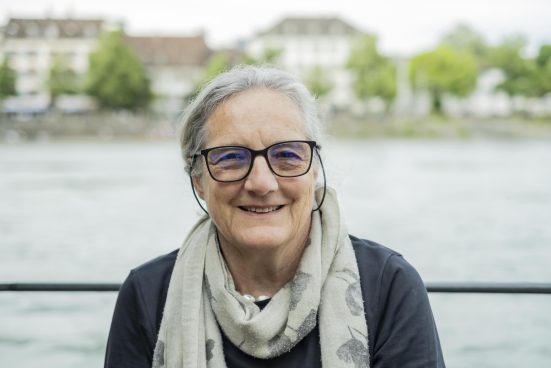 Woman with glasses and gray hair standing in front of a body of water