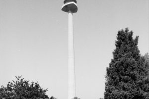 © Architekturzentrum Wien, Sammlung Foto: Friedrich Achleitner, 1990er Jahre s/w Foto mit einem hohen Turm, davor ist eine Straße mit Schienen