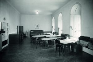 s/w Foto mit Raum mit Tischen, Rundbogenfenstern und einem Foto an der hinteren Wand