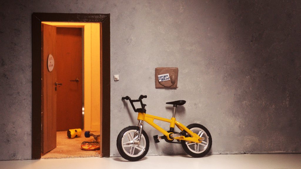 gelbes Kinderfahrrad steht vor einer offen Tür angelehnt an eine Wand