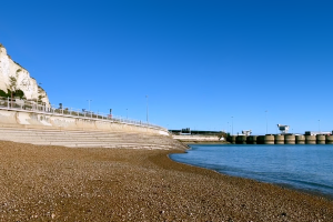 Strand mit Stufen zum Wasser und zum Sand, oberhalb eine Straße und ein heller Felsen