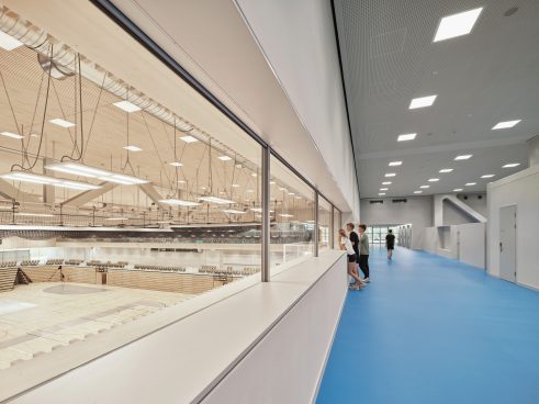 a huge indoor gym with a walkway (blue floor) and windows you can see through