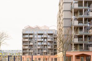 zwei grau-rosa mehrgeschossige Gebäude, davor ist ein Spielplatz zu sehen