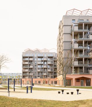 two grey-pink multi-storey buildings, with a playground in front of them