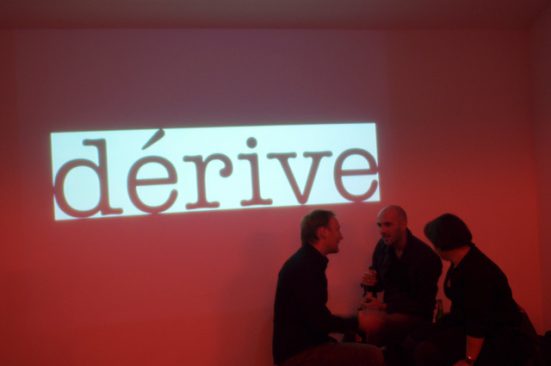 roter Hintergrund vor dem 3 Personen stehen, die miteinander reden. Auf dem roten Hintergrund steht der Schriftzug 