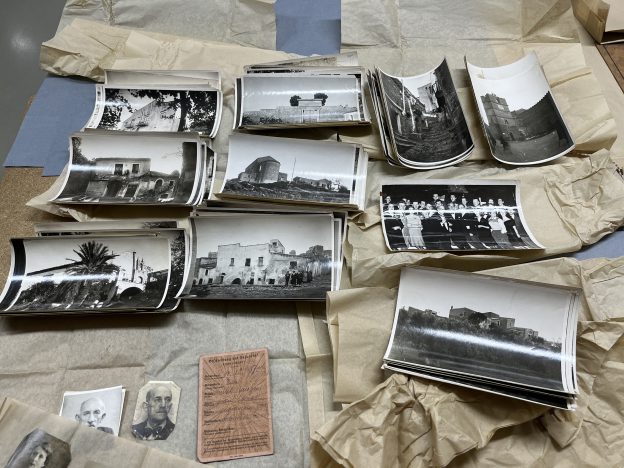 mehrere Fotos in schwarz-weiß die schon älter aussehen, die sich alle nach oben wölben, liegen auf einem Tisch