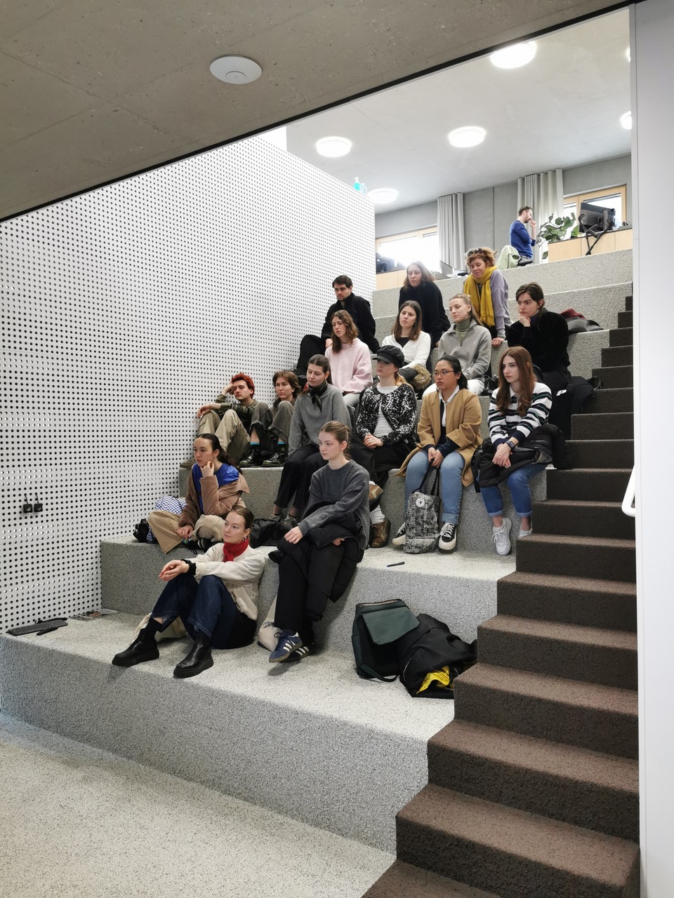 einige Personen, hauptsächlich Jugendliche, sitzen auf einer Treppe und schauen in eine Richtung